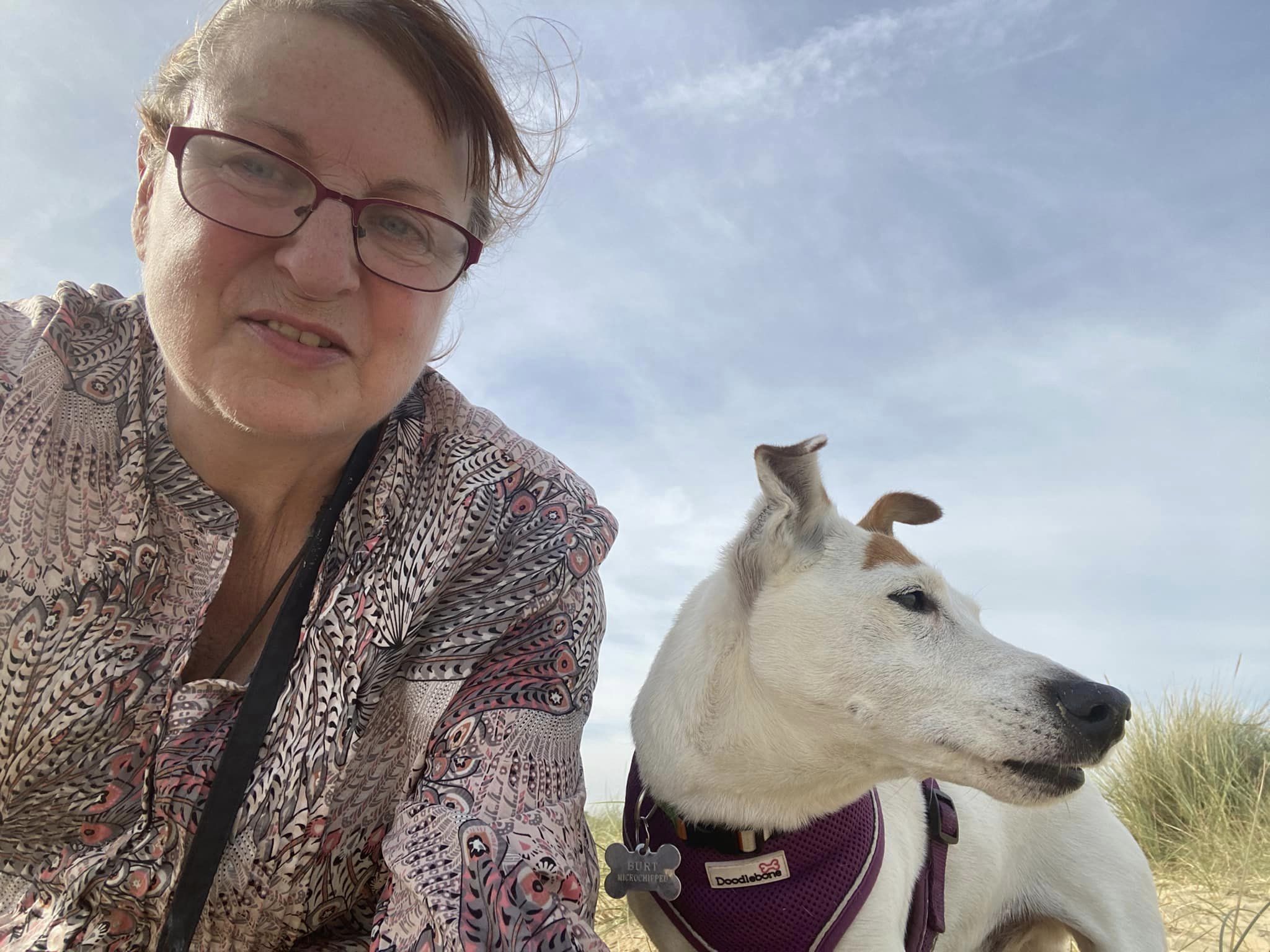 Lyndsay and Burt the jack Russell at the beach with a blue sky in the background